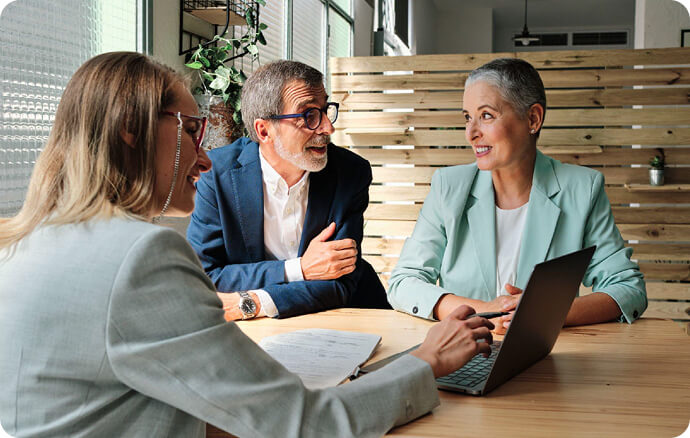 three people conversating while pointing at a laptop