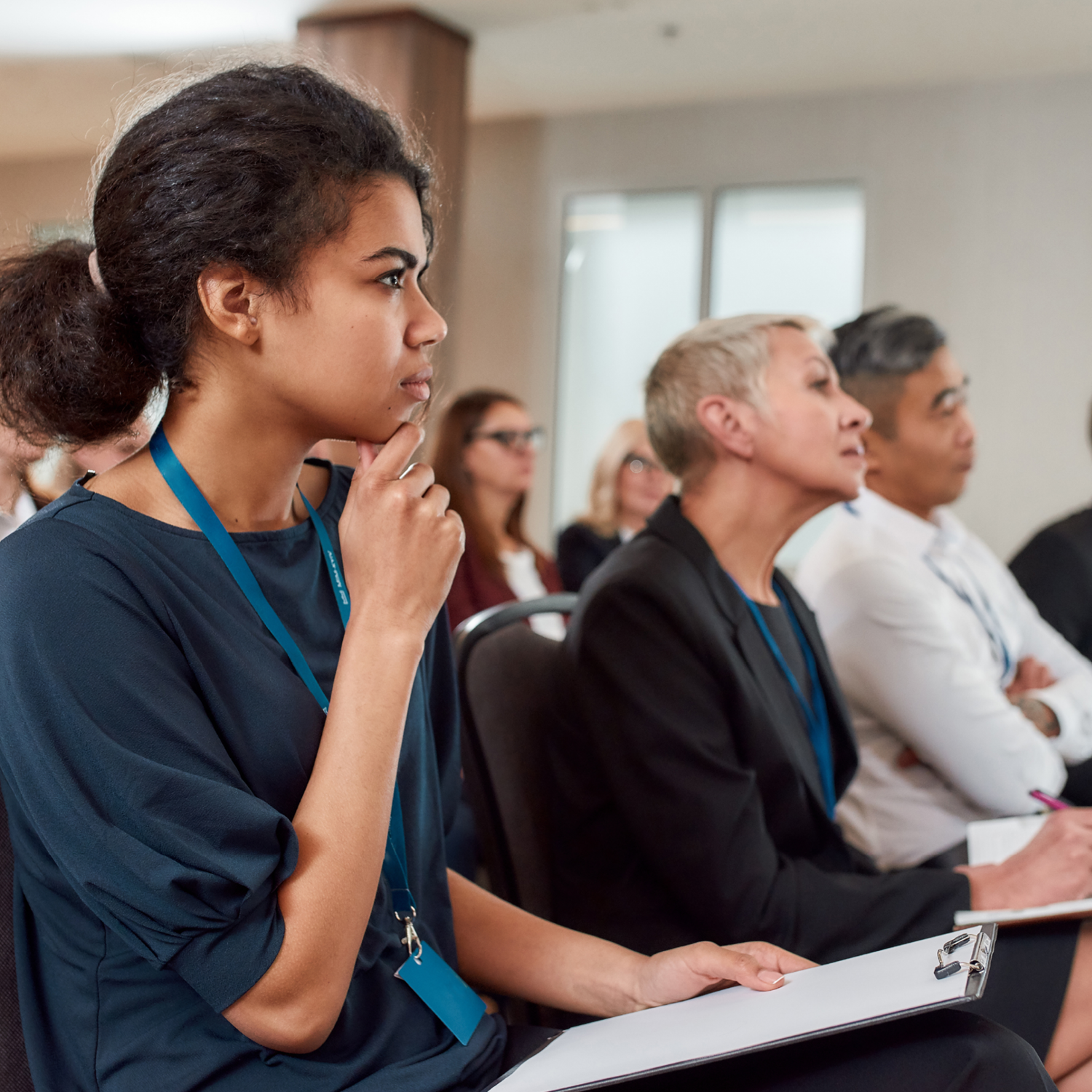 Woman in focus at meeting, people in background paying attention