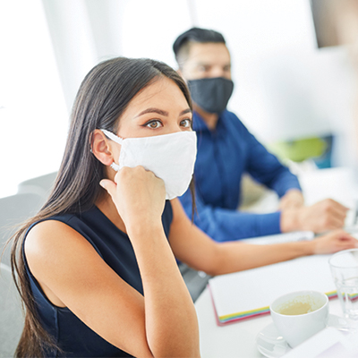 people in masks sitting at table