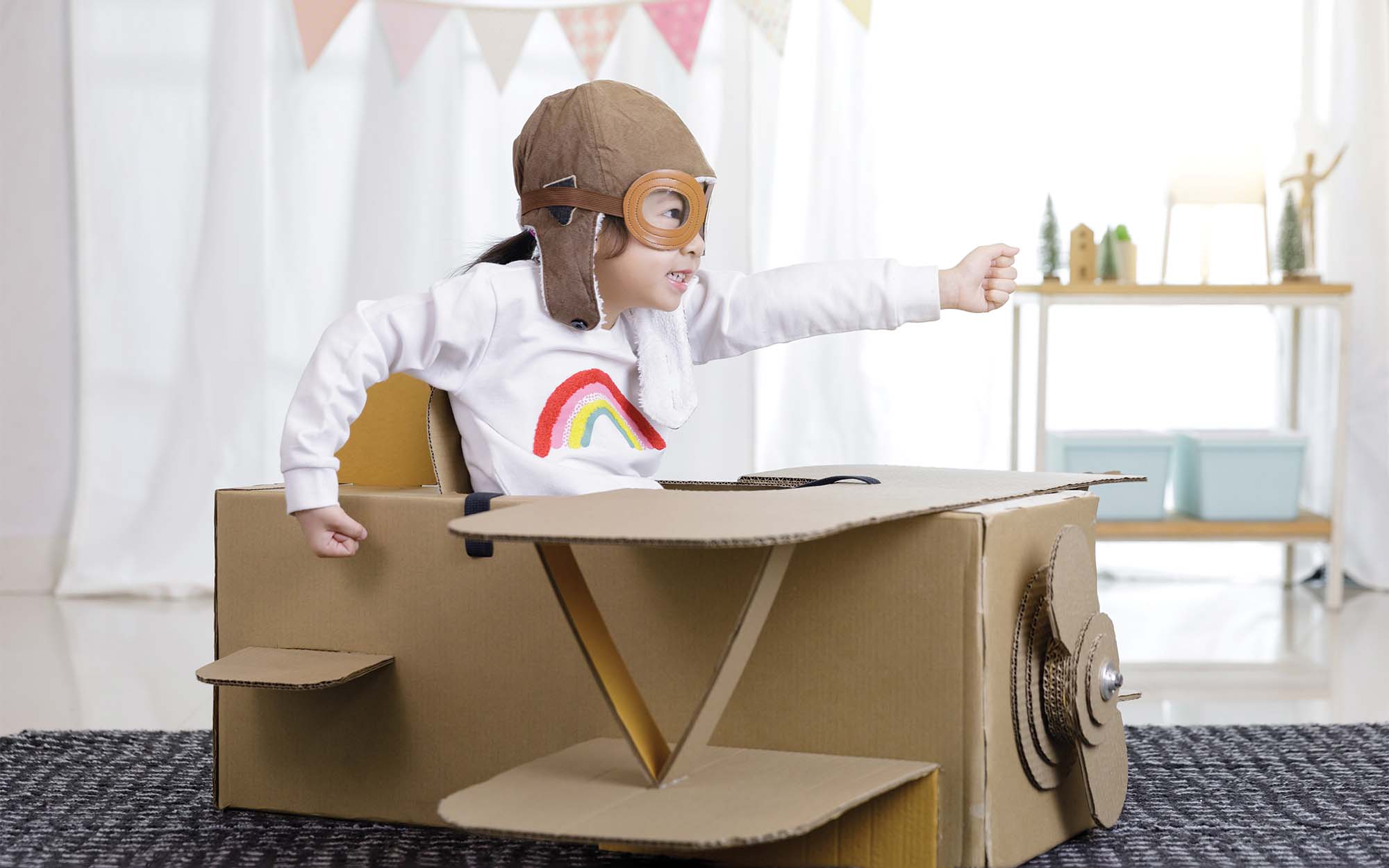 child playing in a cardboard airplane